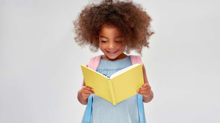 A happy girl smiling while reading a book for kids with autism