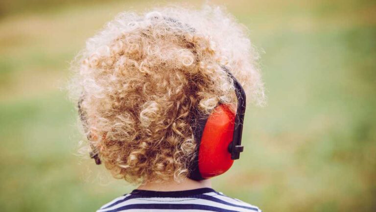 Child with autism wearing noise-canceling headphones, illustrating the window of tolerance and sensory regulation.