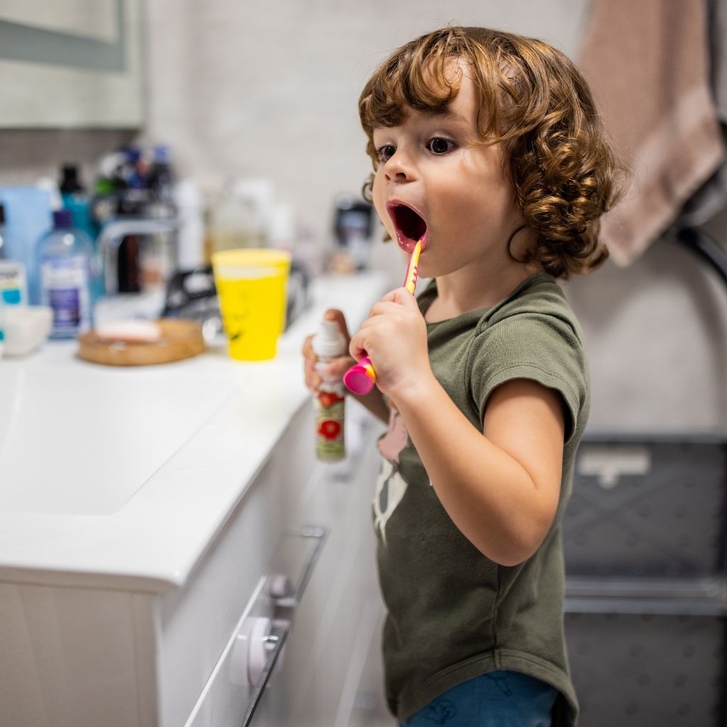 Young child brushing their teeth as part of a daily routine